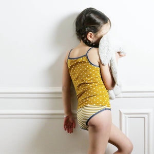 Foto de Little girl in underwear on yellow background, back view